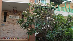 A building with a sign reading "Tamarindo Residences," a brick facade, and a tree with white flowers in front. - Tamarind Residences (Khon Kaen)
