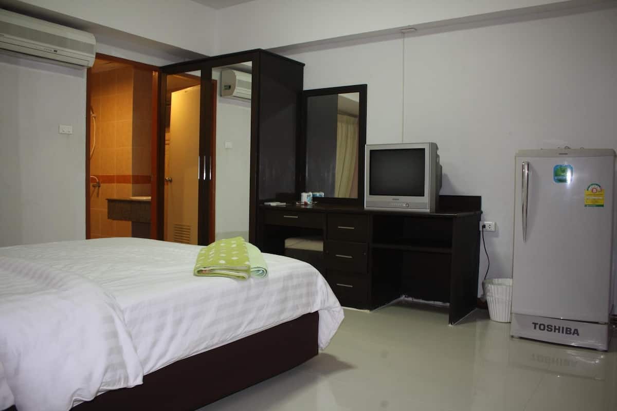 Un dormitorio con una cama, televisión, refrigerador y armario.
