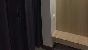 A room with a wooden door, a light switch, and a dark curtain. - Tamarind Residences (Khon Kaen)
