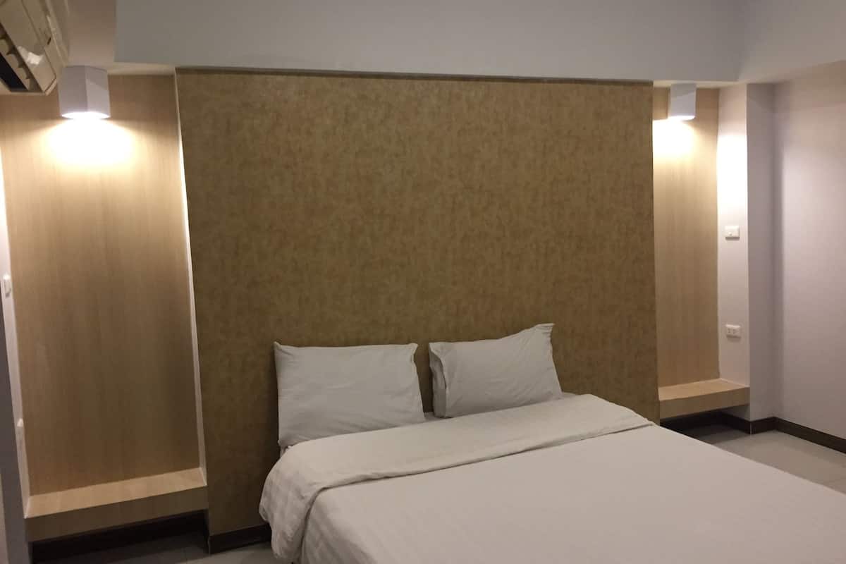 Una habitación de hotel con una cama, un cabecero y dos luces fijadas a la pared.