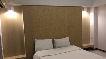 A hotel room with a bed, a headboard, and two wall-mounted lights.