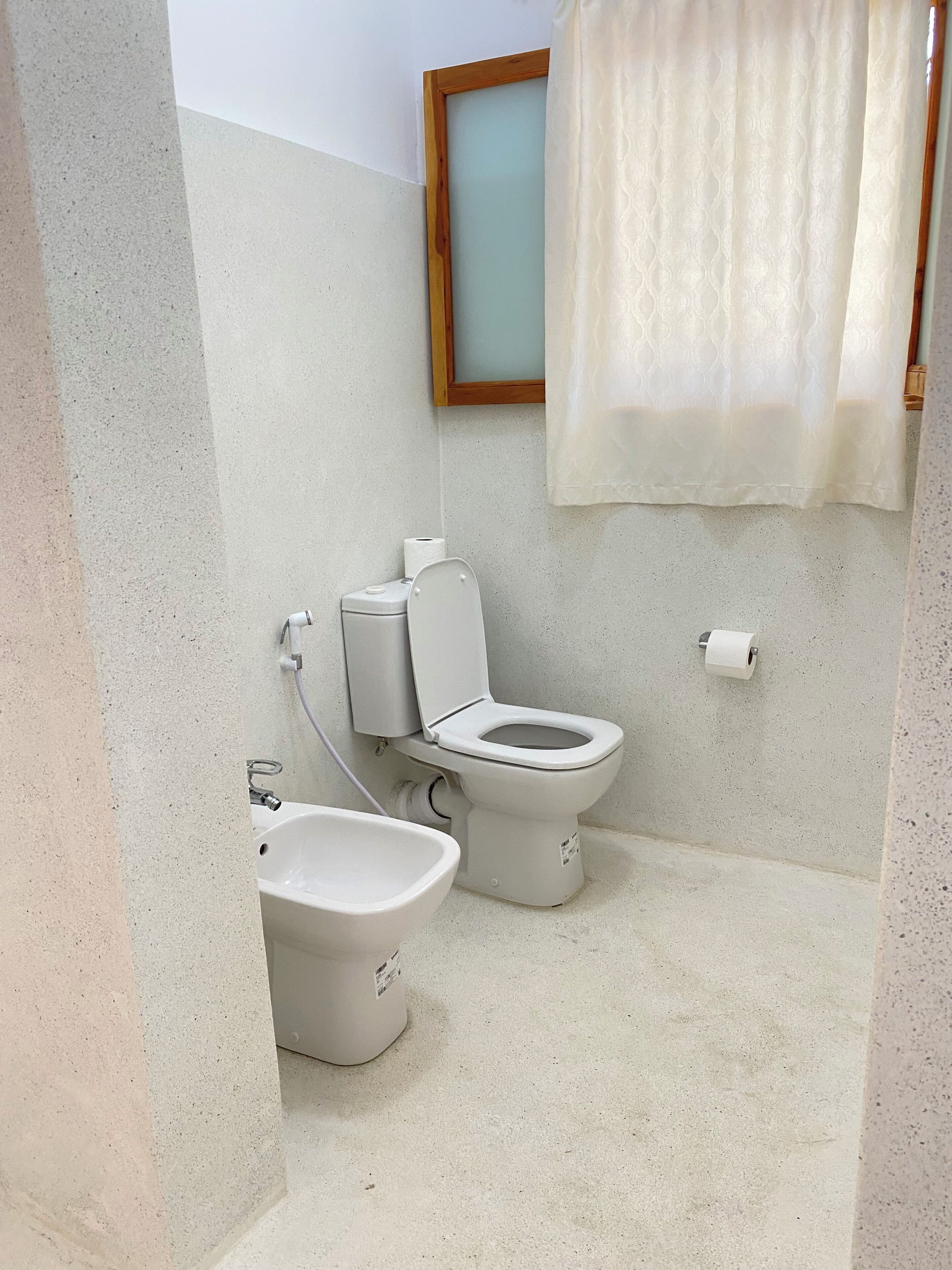 Un baño con inodoro, bidé y lavamanos.