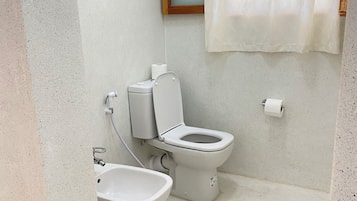Un baño con inodoro, bidé y lavamanos.