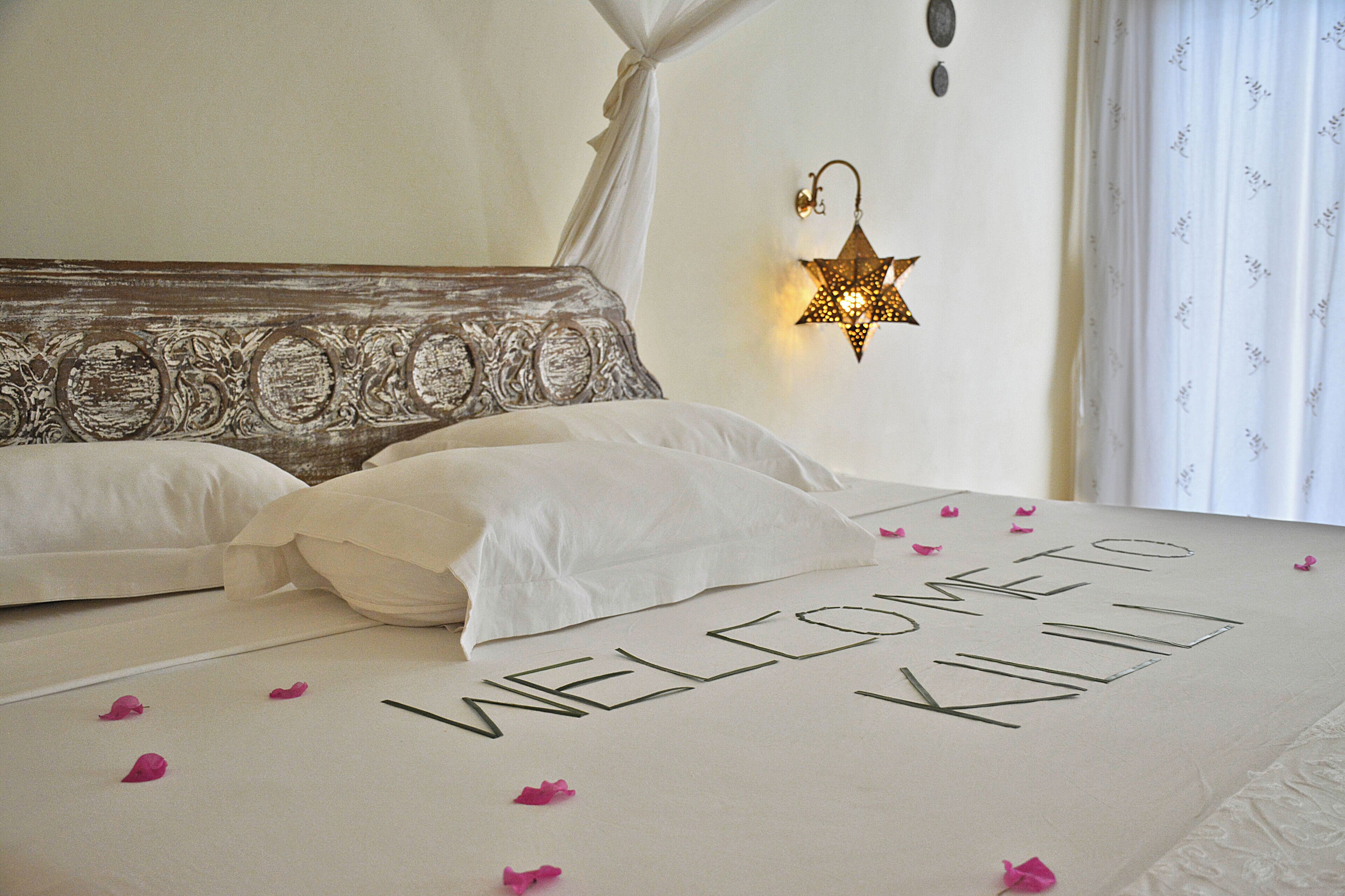 A bed with white linens and a message that reads "WELCOME TO KILILI".