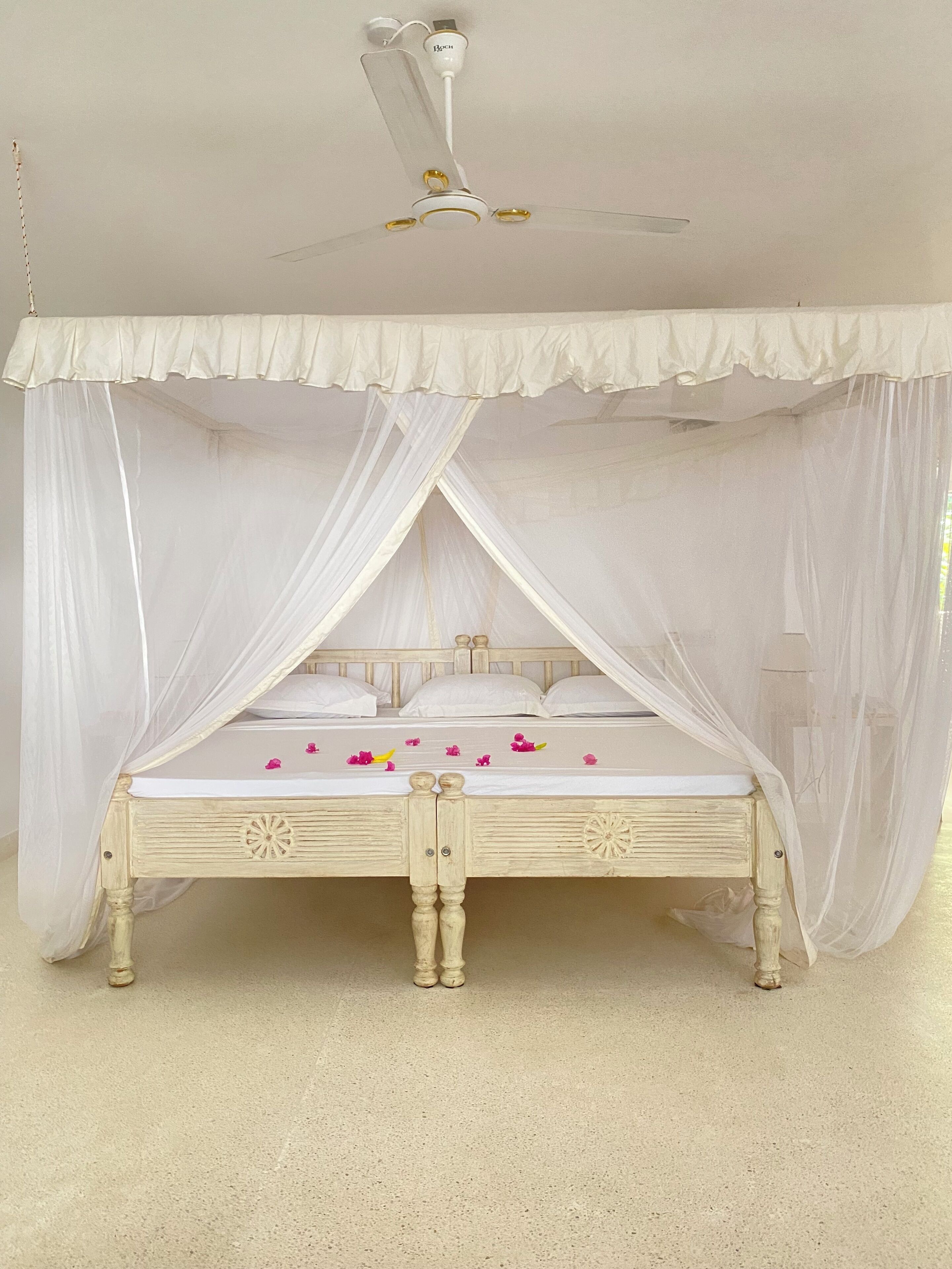 A bed with a canopy, a ceiling fan, and a light fixture.