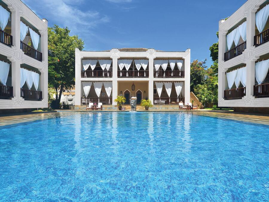 Uma piscina grande com um edifício ao fundo.