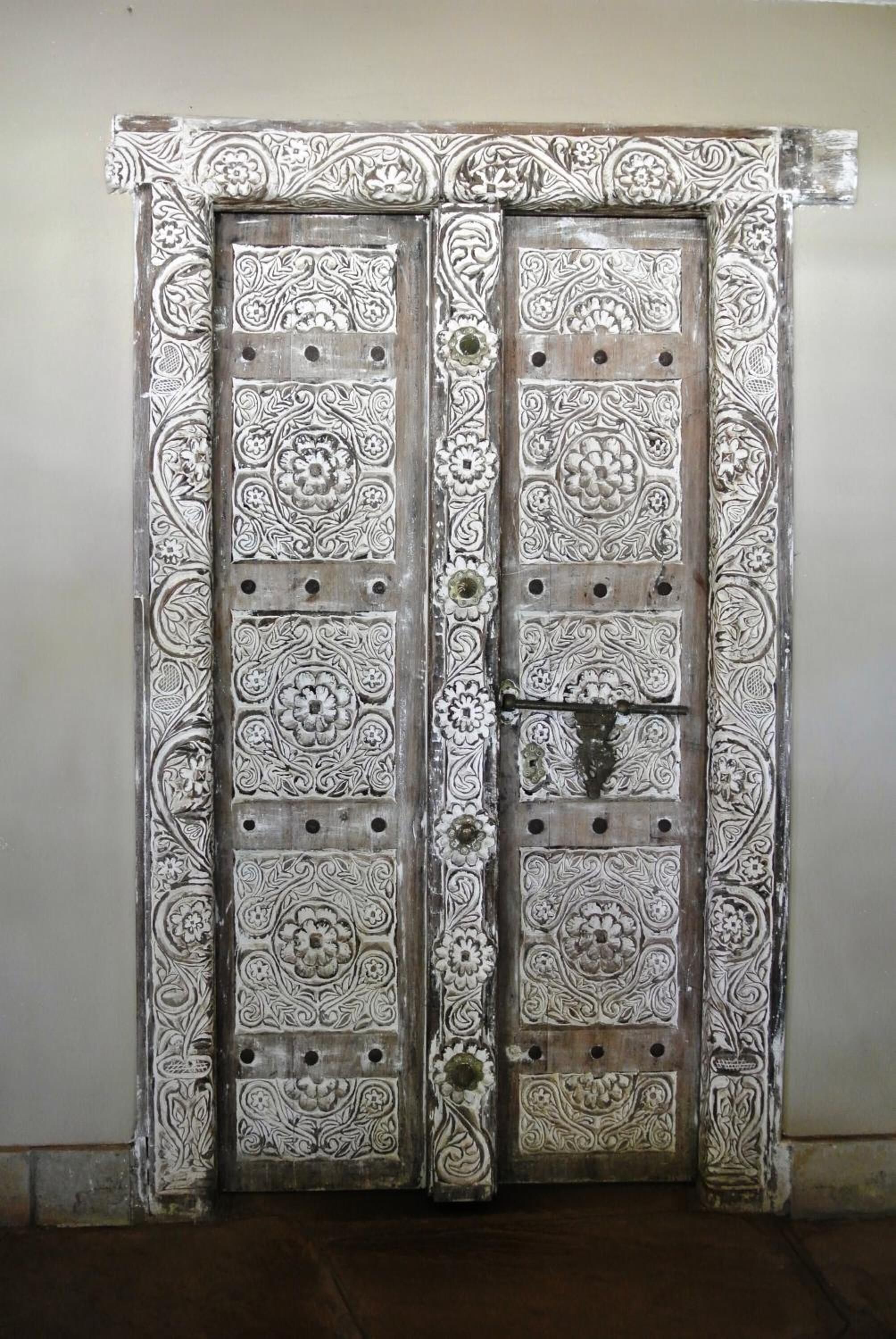 A double door with intricate floral patterns and a central latch.