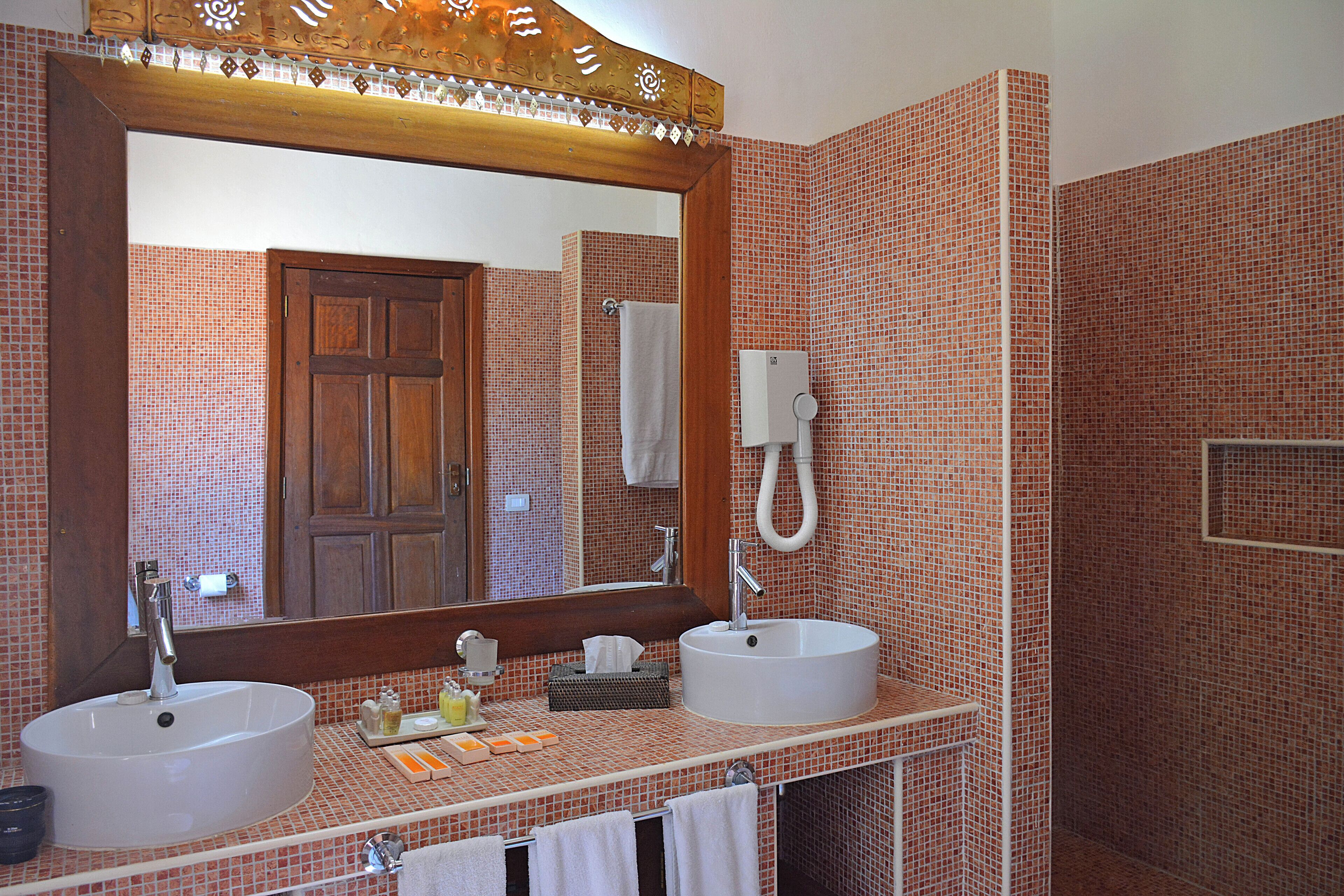 A bathroom with two sinks, a large mirror, and a towel rack.