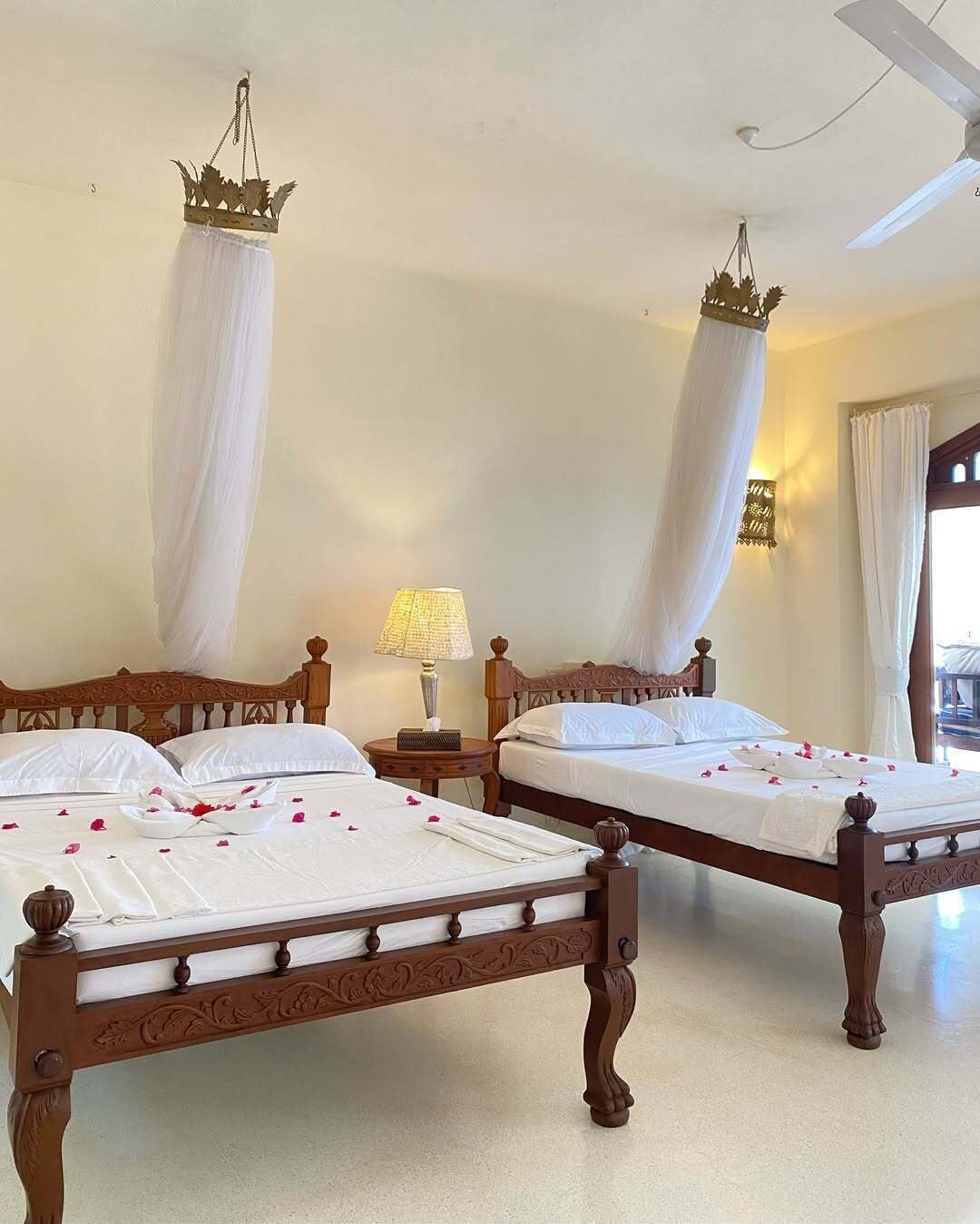 A hotel room with two wooden beds, white bedding, and a canopy bed with a crown-shaped headboard.