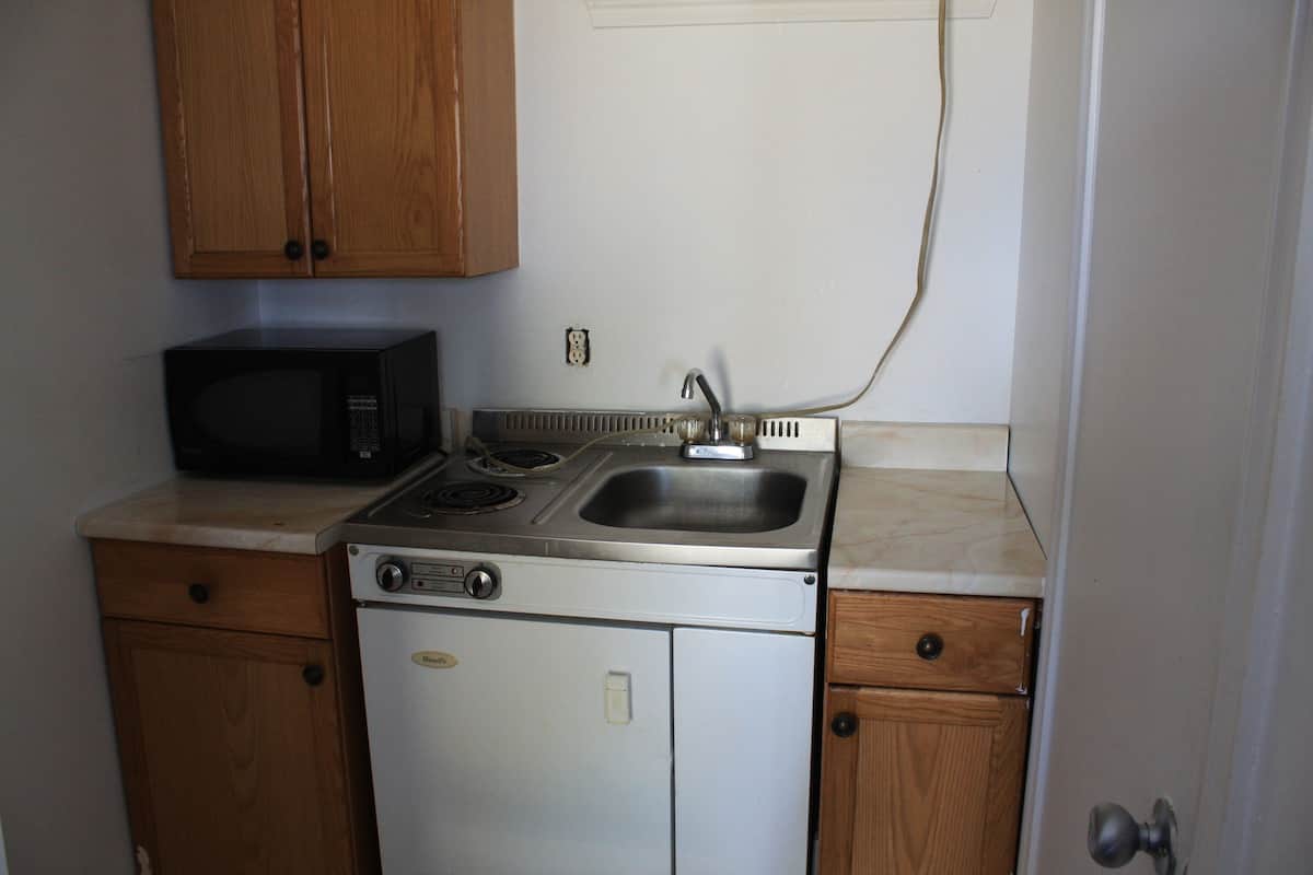 Una cocina compacta con estufa, lavaplatos y microondas.