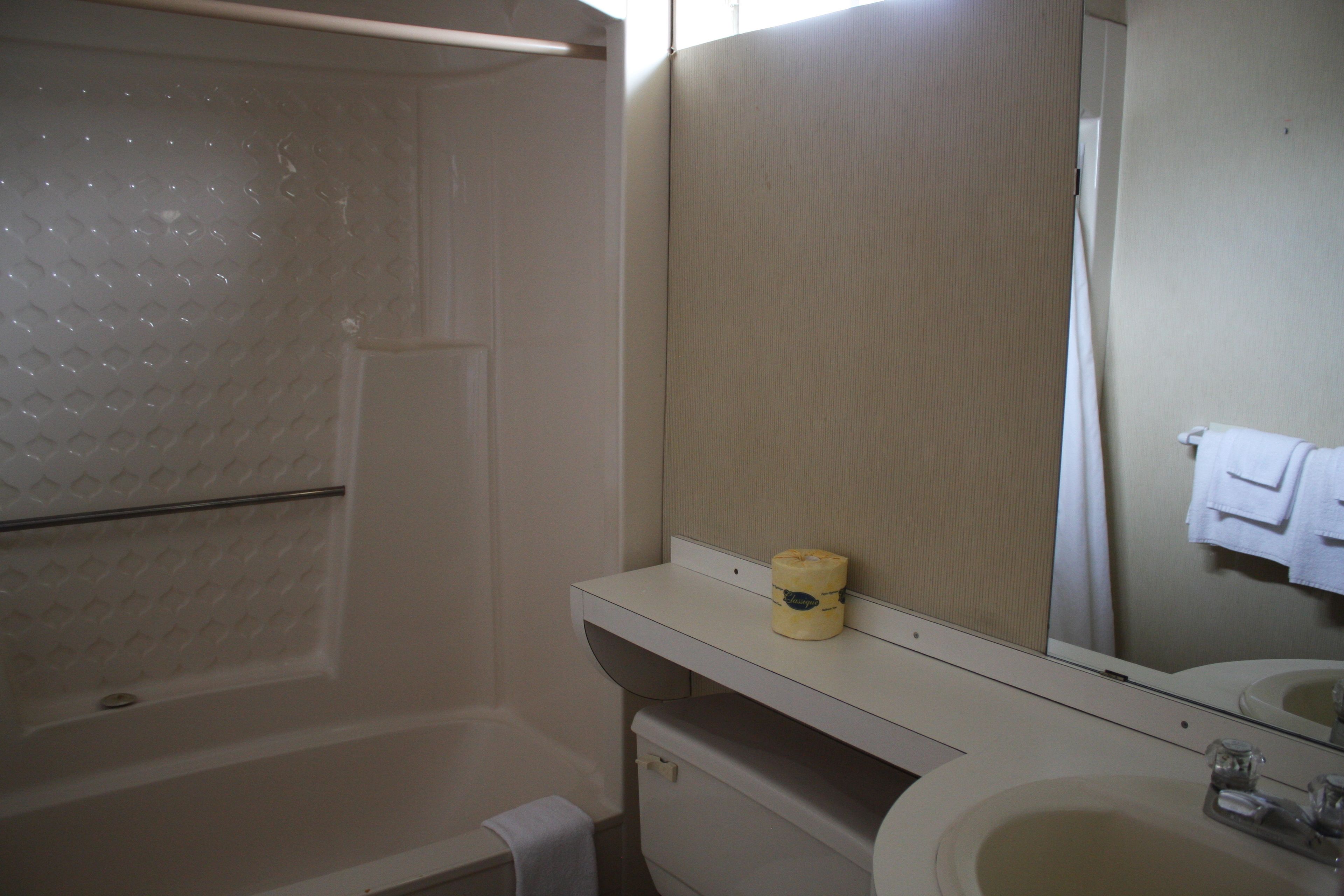 A bathroom with a bathtub, a sink, and a mirror.