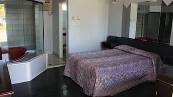 Un dormitorio con una cama grande, ducha integrada y un espejo sobre la cama.