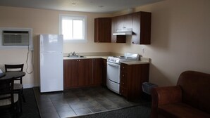 A compact kitchen with a refrigerator, stove, and wooden cabinets. - Grand Motel Saint-Hubert (Longueuil)