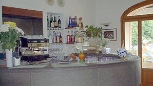 A bar area with a curved counter, shelves with bottles, and a view through a glass door.