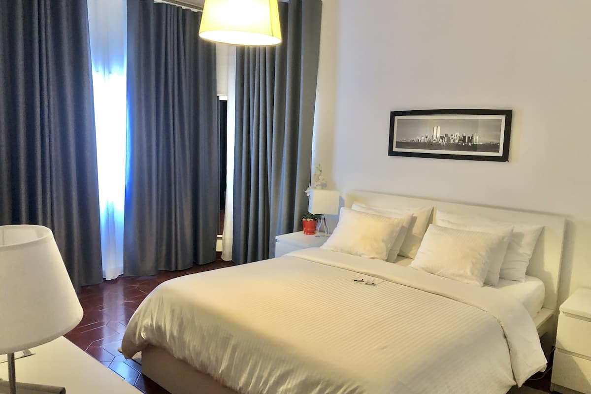 Une chambre d’hôtel avec un grand lit, une table de chevet, une lampe et un tableau encadré au mur.
