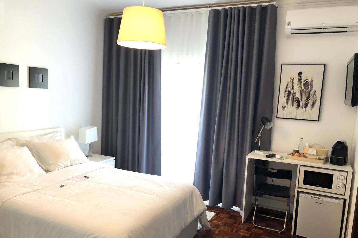 Une chambre d’hôtel équipée d’un lit, d’un bureau avec une lampe, d’un four à micro-ondes et d’un petit réfrigérateur.