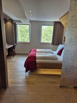 Un dormitorio con cama, escritorio y dos ventanas.