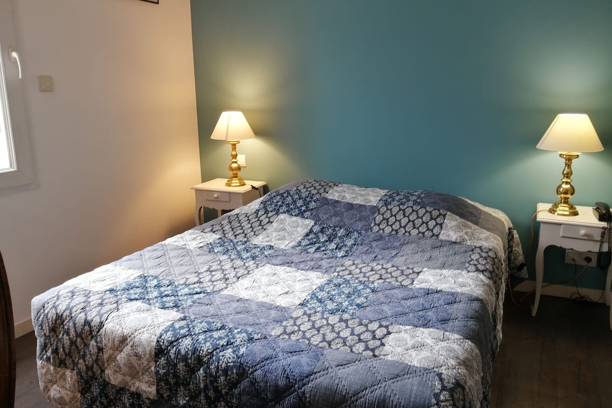 A bedroom with a bed, two bedside tables, a lamp on each table, and a painting on the wall.