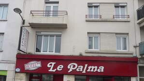 A hotel named "Le Palma" with a red awning, a visible entrance, and a sign indicating it is a hotel. - Hotel Le Palma (Angouleme)