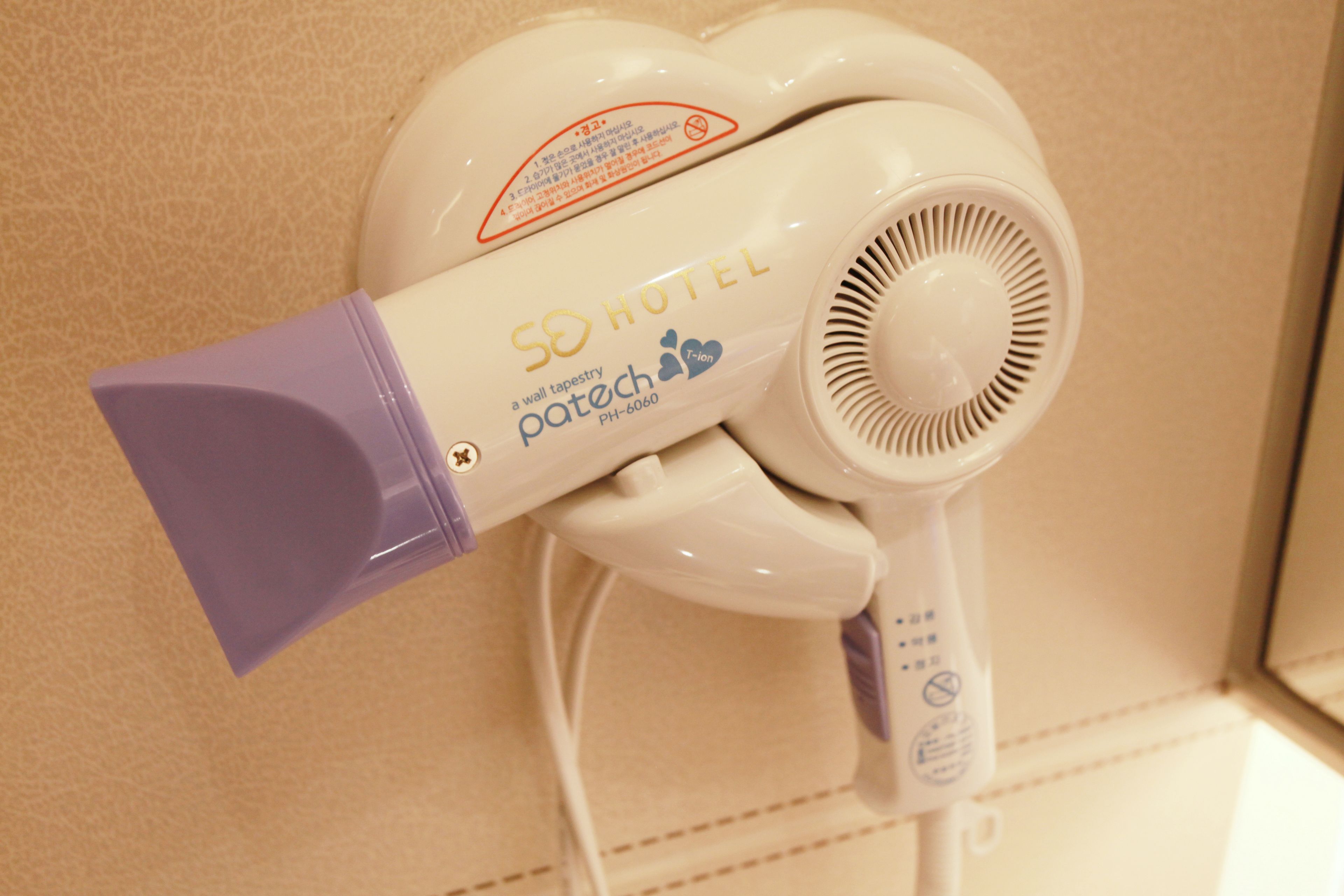 A wall-mounted hair dryer with a purple nozzle, labeled "50 HOTEL a wall tapestry patech PH-6060".