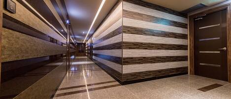 A modern hallway with a polished floor, striped wall panels, and a door on the right.