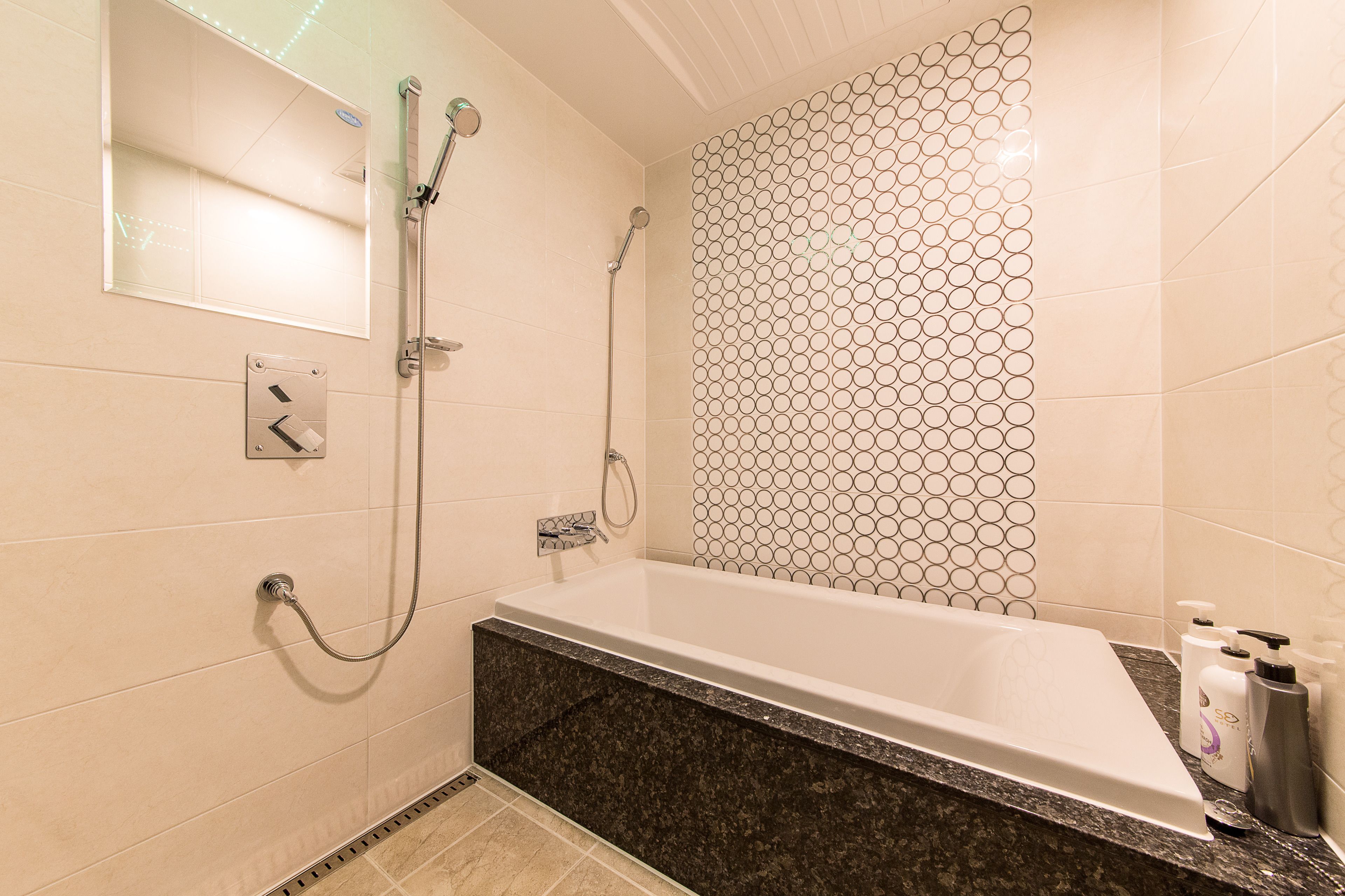 A modern bathroom with a freestanding bathtub, a shower with a handheld showerhead, and a wall-mounted mirror.