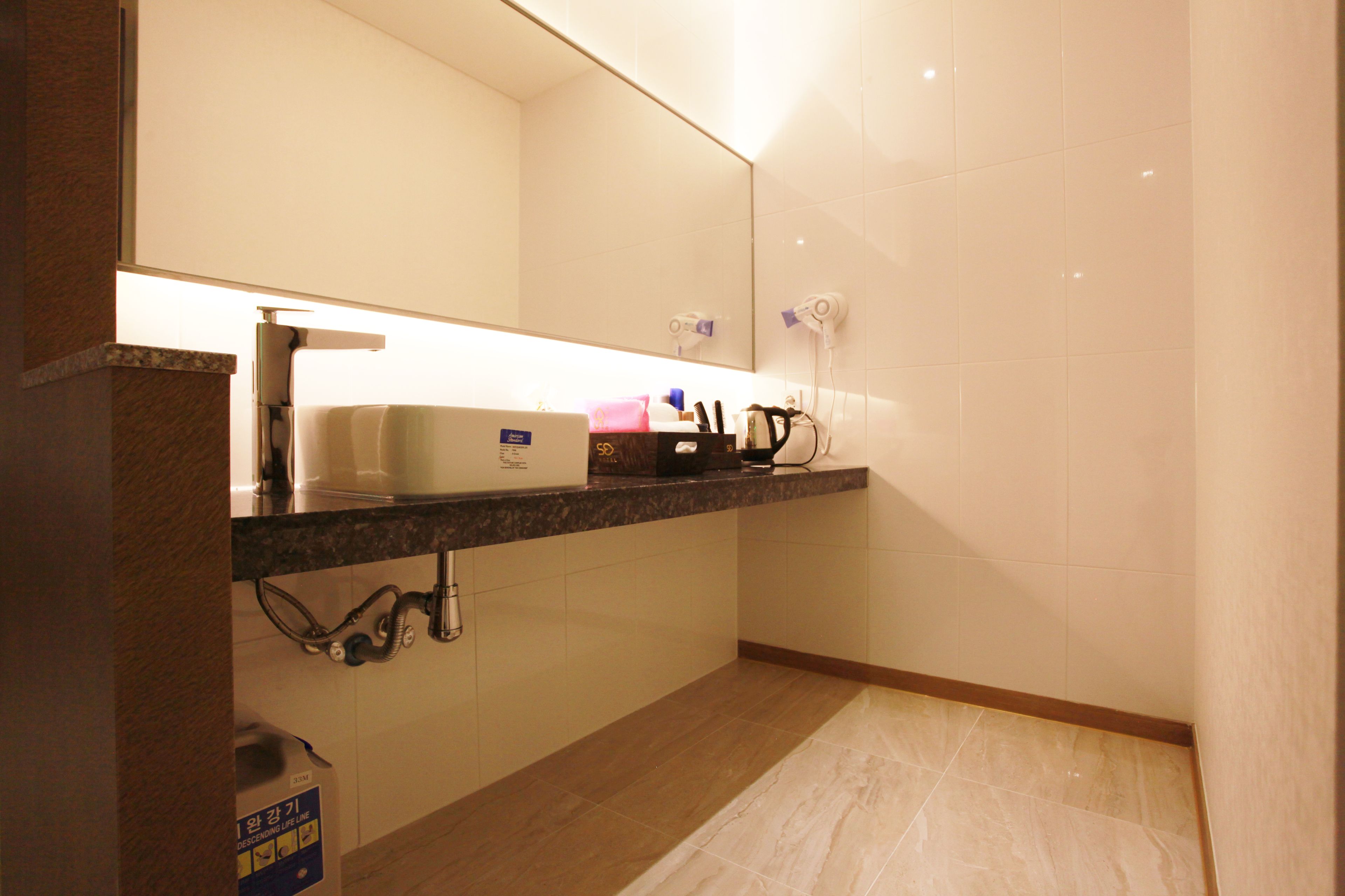 A modern bathroom with a marble countertop, a sink, a mirror, and a towel rack.