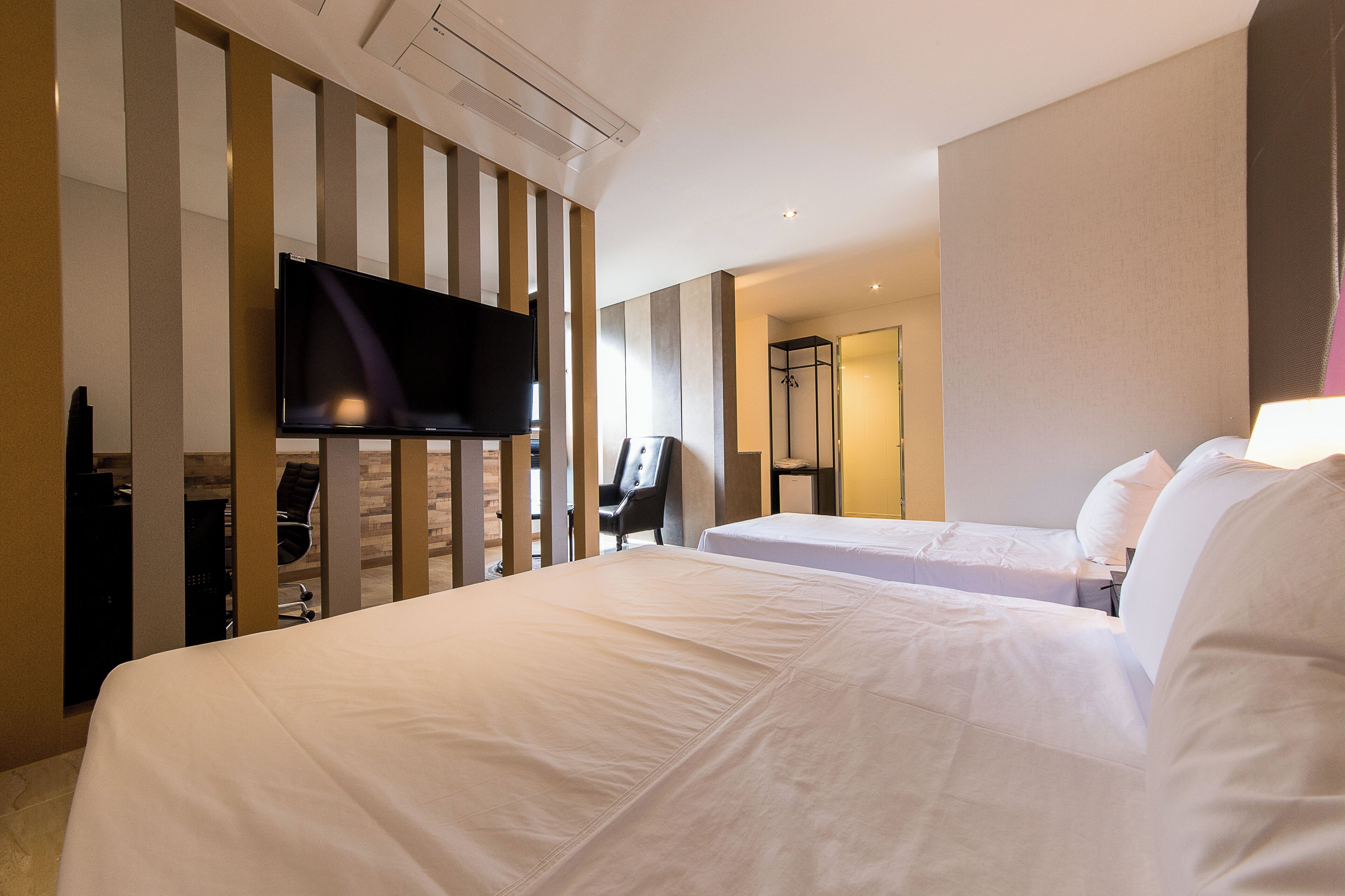 A hotel room with two beds, a flat-screen TV, a desk, and a walk-in closet.