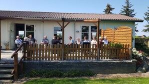 Un bâtiment avec un toit en tuiles et une clôture en bois à l’avant.