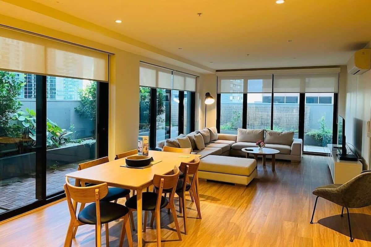 Una sala de estar moderna con comedor, ventanas amplias y un sofá.