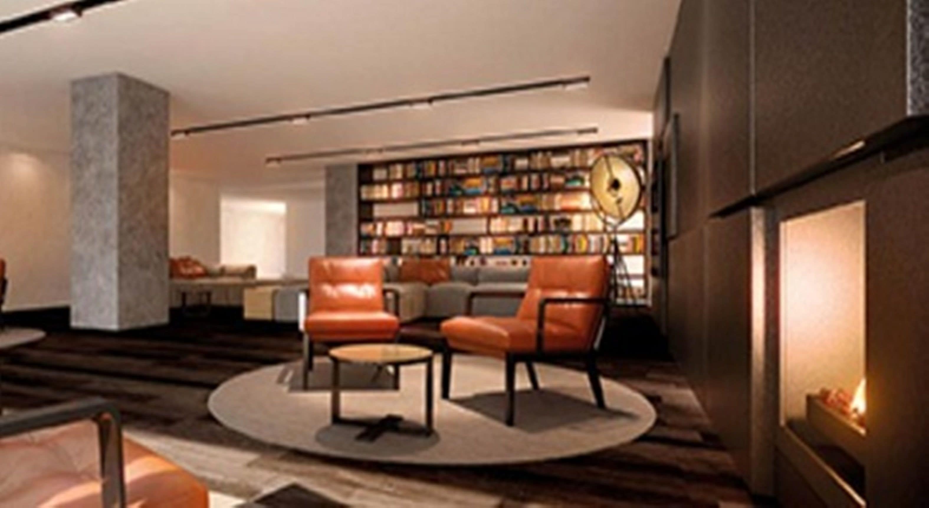 A modern living room with leather armchairs, a fireplace, and a bookshelf filled with books.