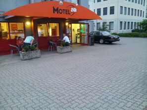 Un motel con asientos al aire libre y un coche estacionado cerca.