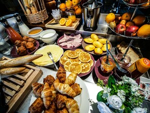 Un bufé de desayuno con diversas opciones de comida, incluyendo pasteles, frutas y bebidas.