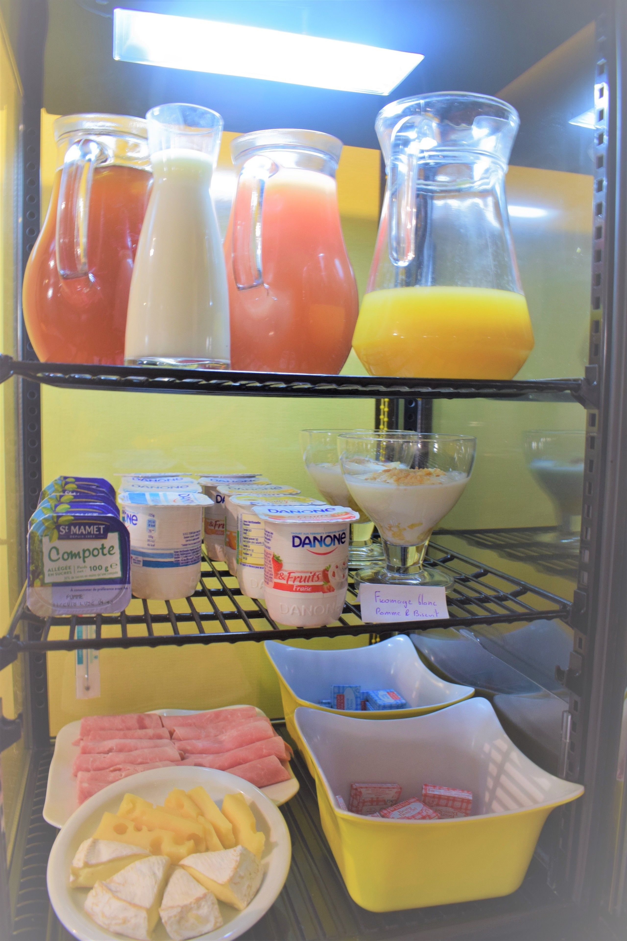 Un refrigerador lleno de diversos alimentos, incluyendo productos lácteos, jugos y aperitivos.