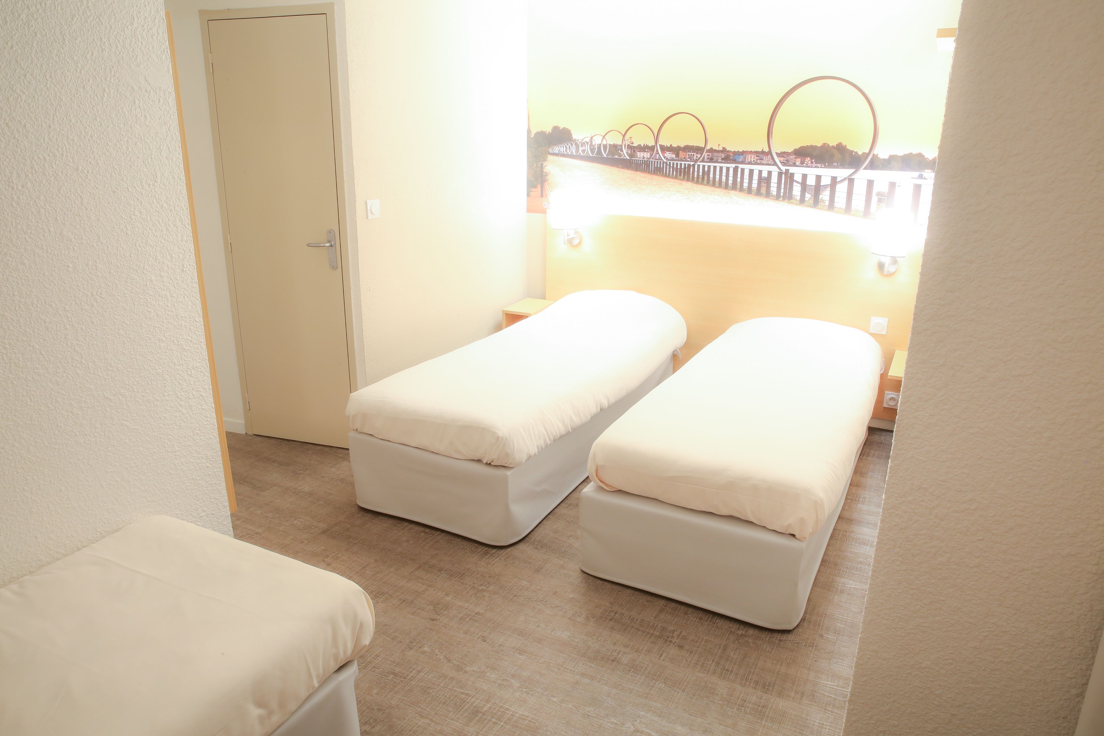 Una habitación con dos camas individuales, una puerta y vista al frente de agua.