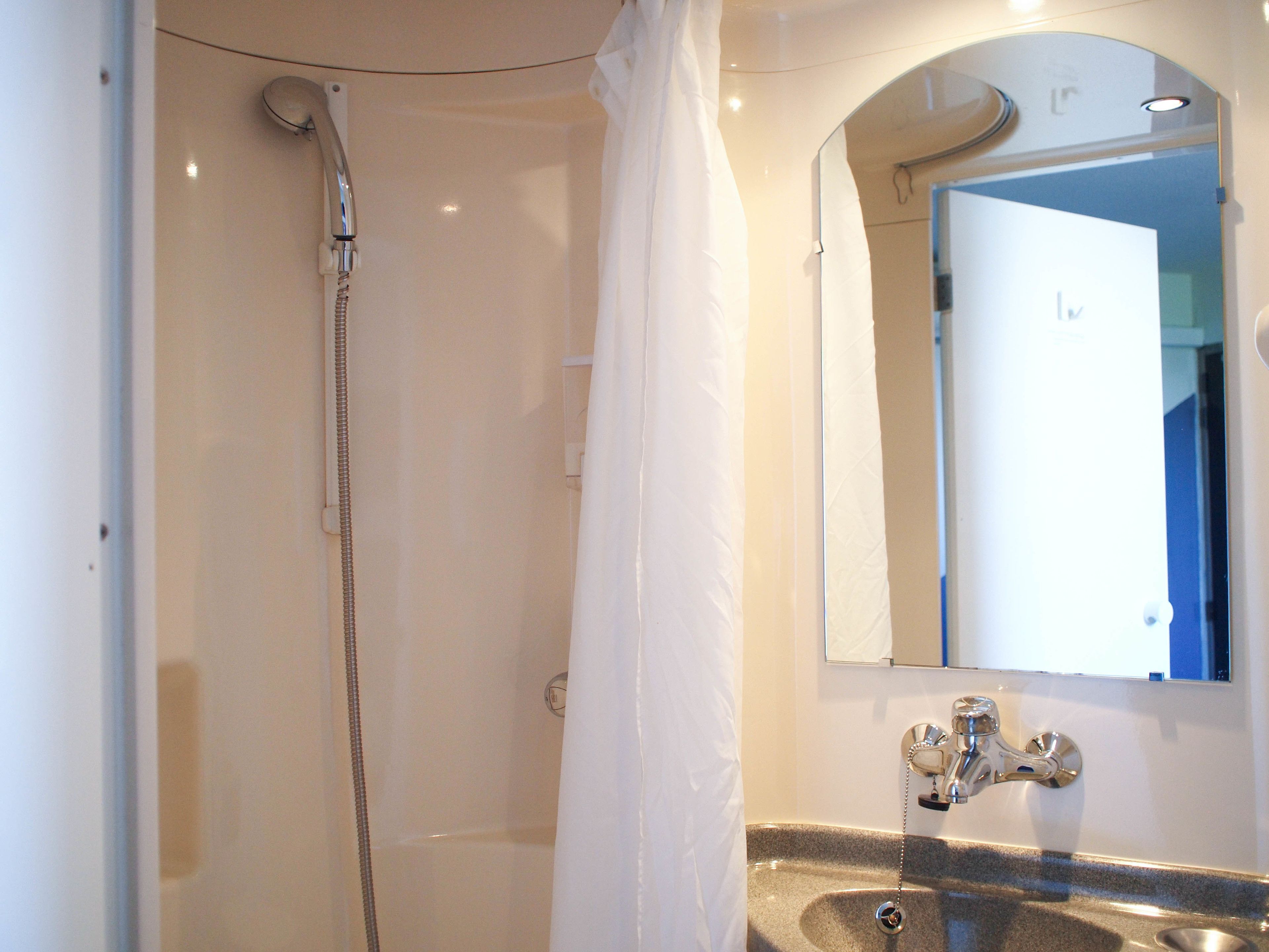 A bathroom with a shower, a sink, and a mirror.