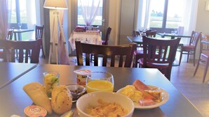 A breakfast setting with a table set for two, including a bowl of cereal, a glass of orange juice, and a plate of eggs. - Hôtel Inn Design Châteaubriant (Chateaubriant)