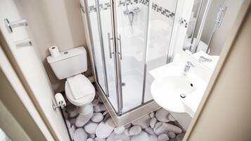 A bathroom with a glass-enclosed shower, a toilet, and a sink.