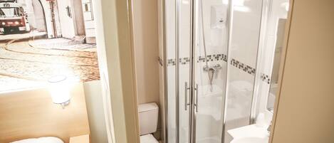 A bathroom with a glass-enclosed shower, a toilet, and a sink.