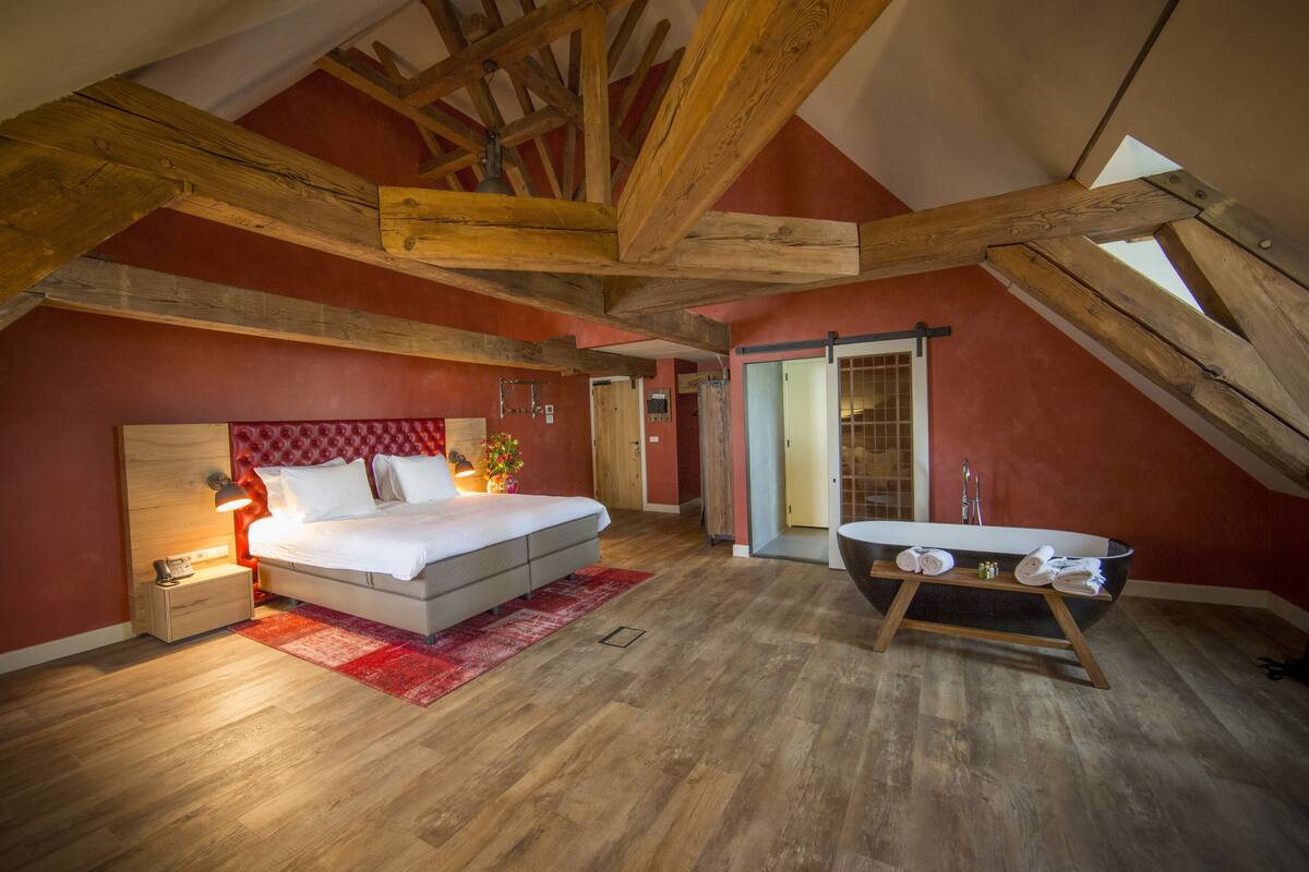 A bedroom with a bed, bedside table, lamp, and a large window.
