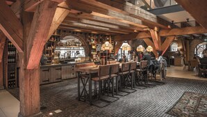 Un área de bar espaciosa con vigas de madera, paredes de ladrillo y diversas opciones de asientos.