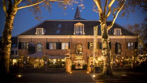 Un edificio histórico con una torre destacada, ventanas de arco y una entrada bien iluminada.