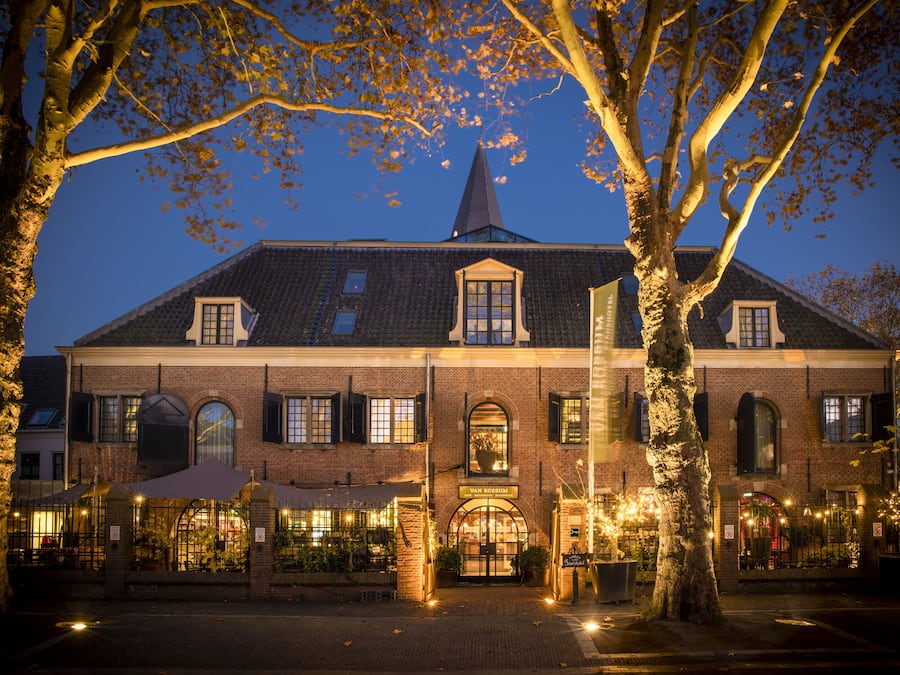 A historic building with a prominent tower, arched windows, and a well-lit entrance.