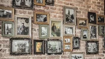 A brick wall with multiple framed photographs of various scenes and people.