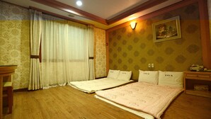 A hotel room with two single beds, wooden flooring, a desk, and a nightstand. - Jeju Olleh Hotel (Jeju City)
