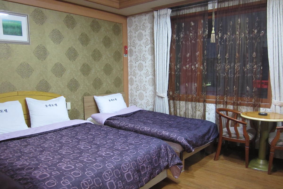 Habitació d'hotel amb dos llits, una taula rodona petita i una cadira.