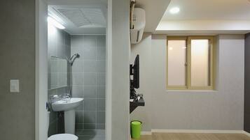 A bathroom with a toilet, sink, and shower. There is a green trash bin and a towel rack.