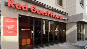 Exterior de Red Guest House, con un letrero que muestra servicios como baño privado, internet, desayuno, ascensor, televisión por cable, información turística y cocina.