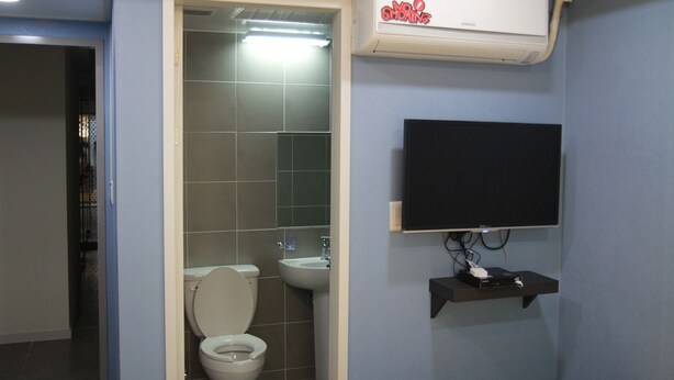 A bathroom with a toilet, sink, and a mounted television. - Red Guest House (Seoul)