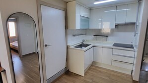 Una cocina compacta con armarios blancos, horno integrado y lavamanos.